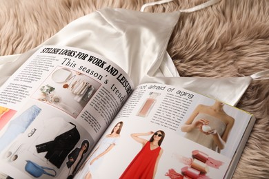 Photo of Open magazine and night dress on beige fur