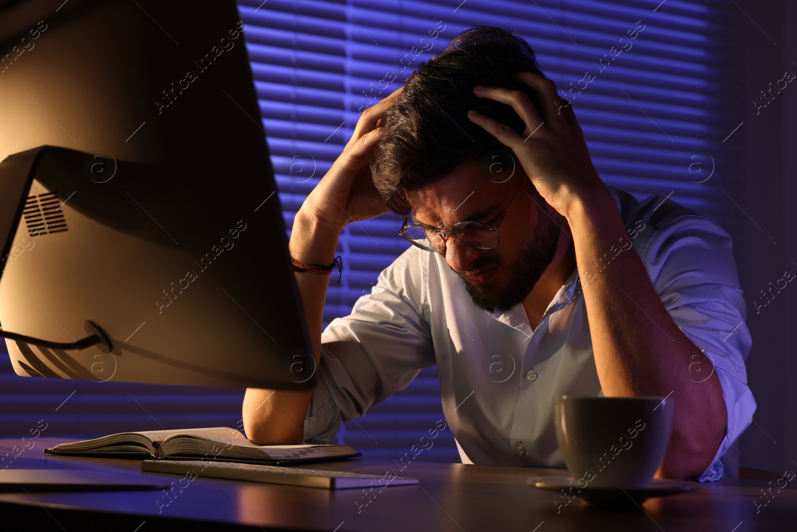 Photo of Tired young man working late in office