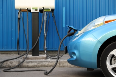 Photo of Charging modern electric car from station outdoors