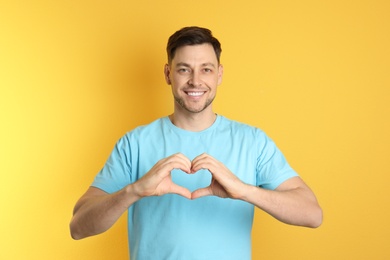 Photo of Portrait of man making heart with his hands on color background