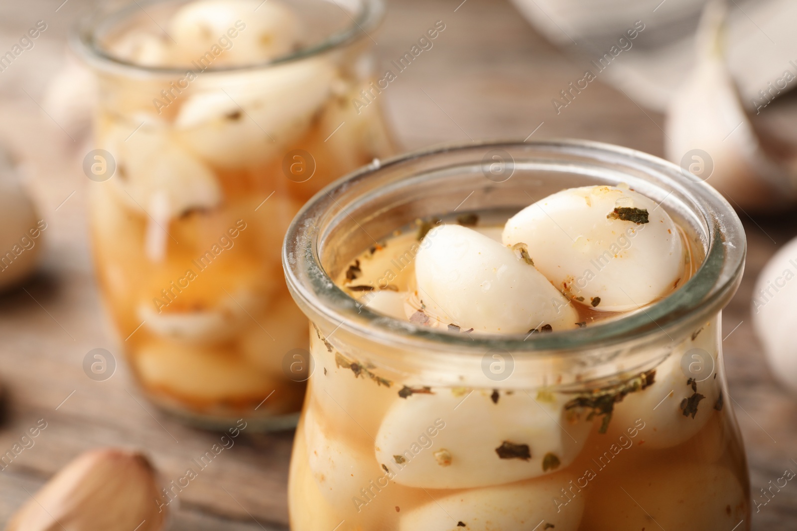 Photo of Preserved garlic in glass jar on table, closeup