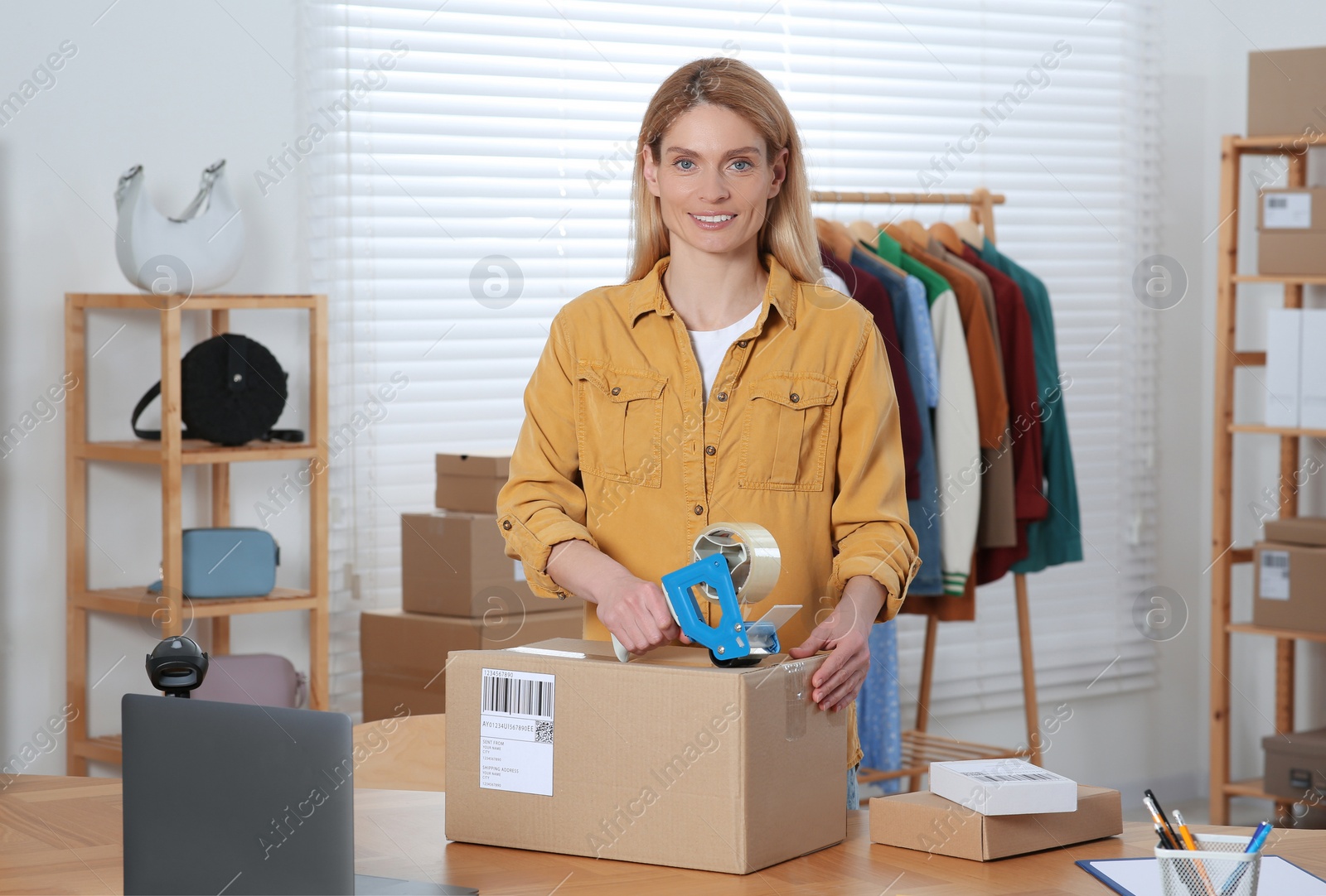 Photo of Seller taping parcel at workplace. Online store