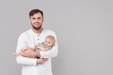 Father with his cute baby on grey background, space for text