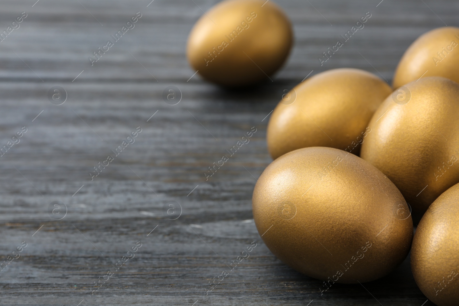 Photo of Gold eggs on wooden background, space for text