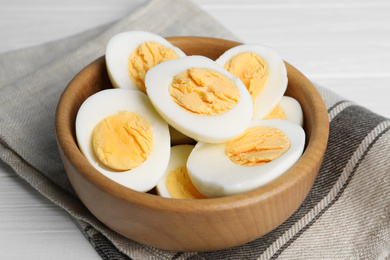 Photo of Cut hard boiled chicken eggs in wooden bowl on table
