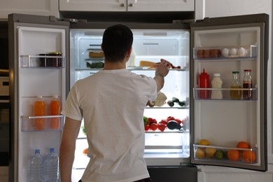 Man near refrigerator in kitchen, back view