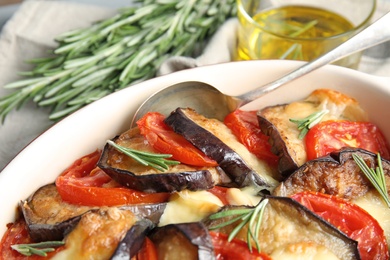 Baked eggplant with tomatoes, cheese and rosemary in dishware, closeup