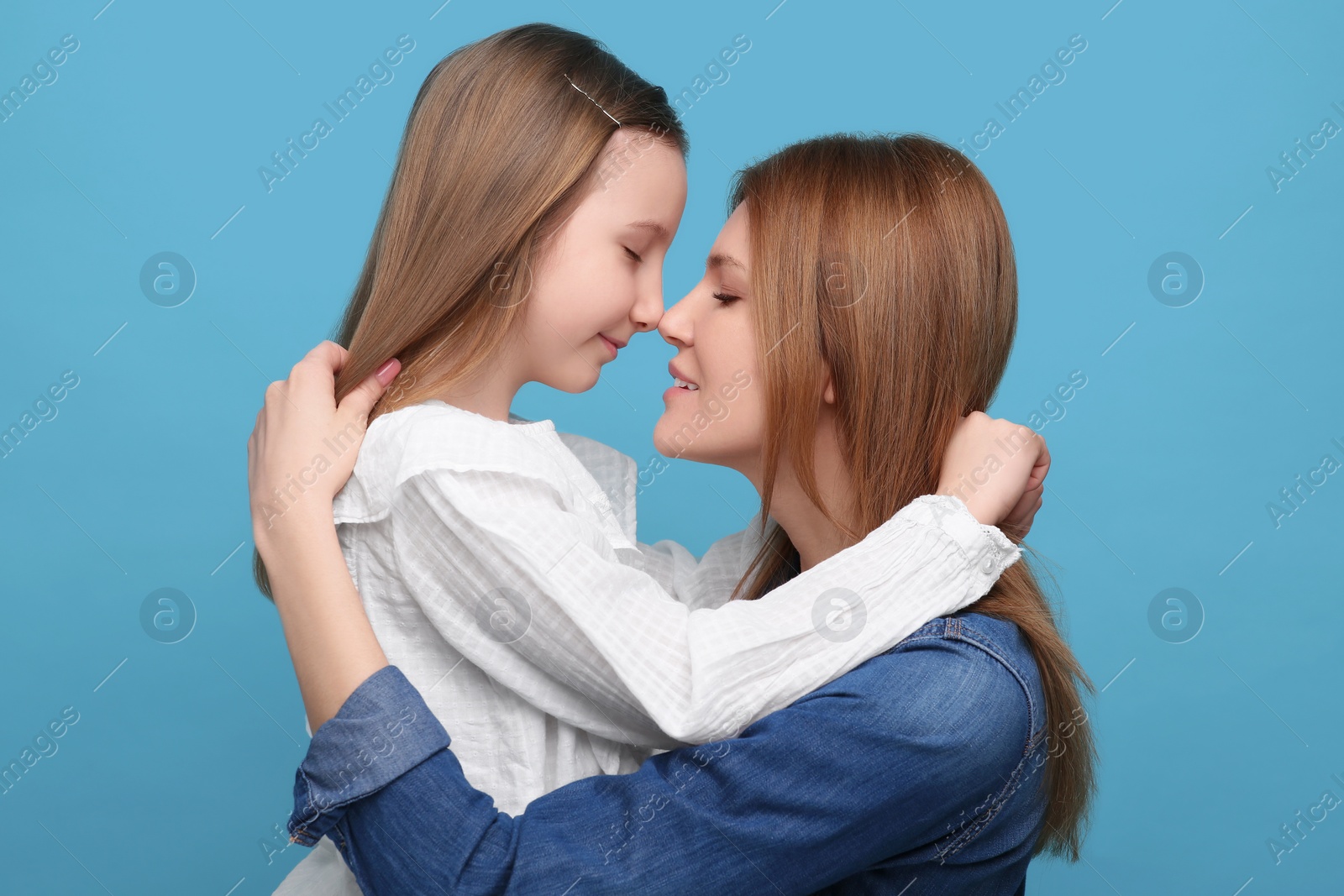 Photo of Portrait of mother and her cute daughter on light blue background