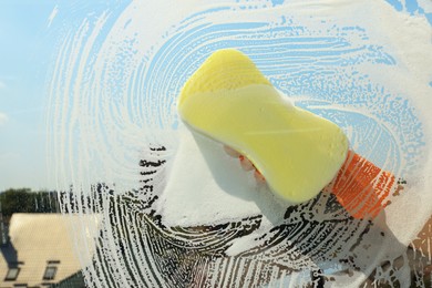 Person cleaning glass with sponge, view from inside