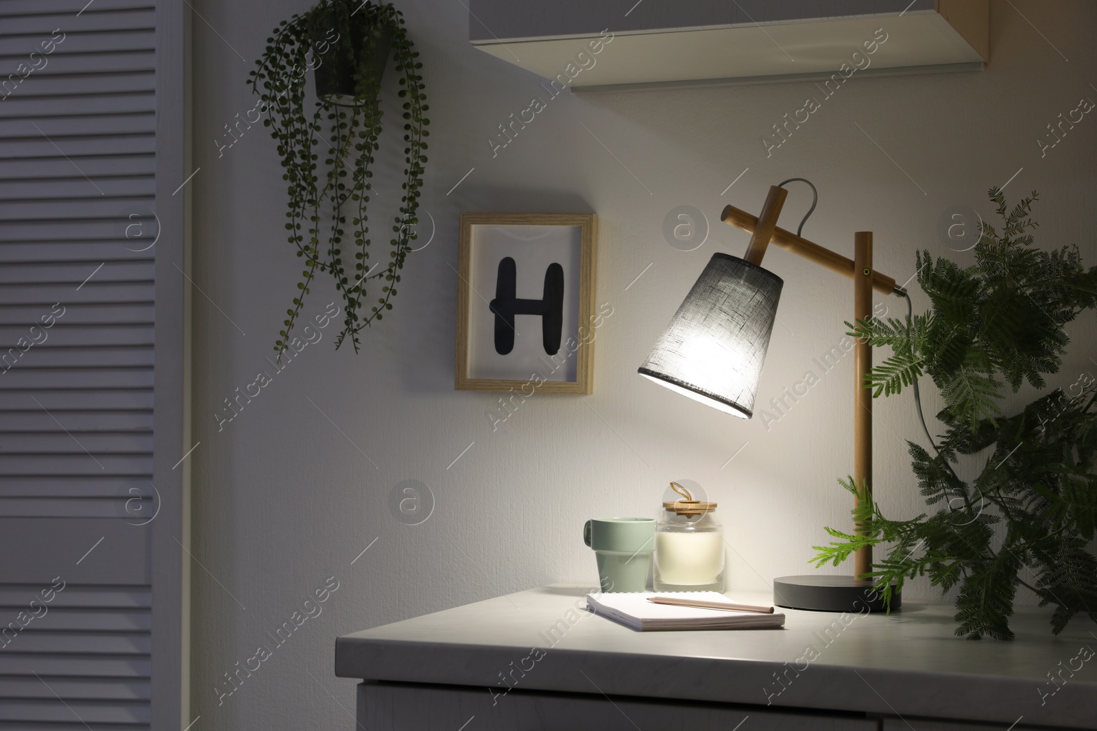 Photo of Stylish lamp and decor on white cabinet in room. Interior element