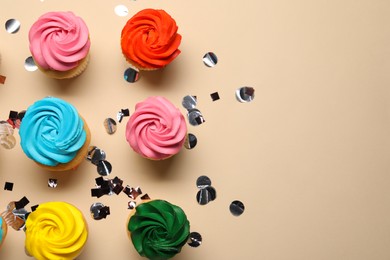 Photo of Delicious cupcakes with bright cream and confetti on beige background, flat lay. Space for text