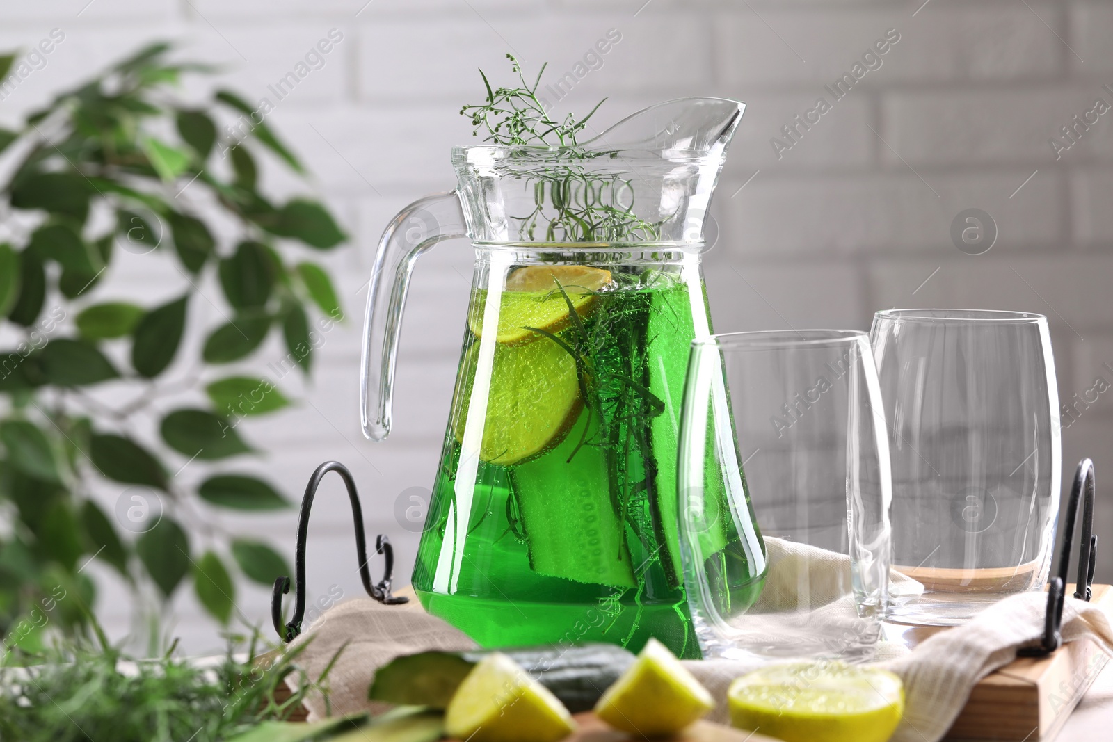 Photo of Jug of homemade refreshing tarragon drink and glasses on table