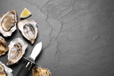 Photo of Fresh oysters with lemon and knife on black table, flat lay. Space for text