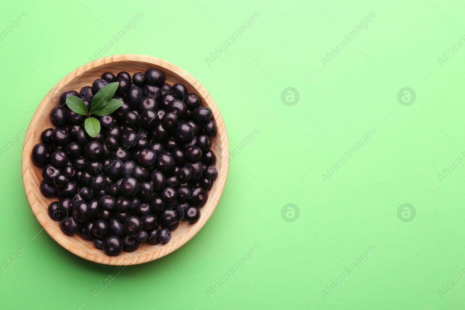 Photo of Fresh acai berries on light green background, top view. Space for text