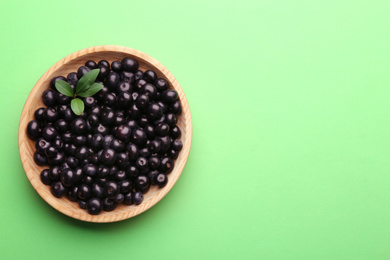 Fresh acai berries on light green background, top view. Space for text