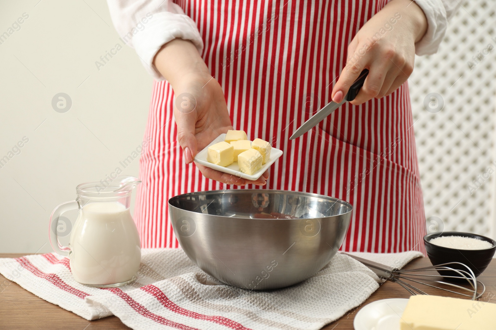 Photo of Woman adding fresh butter into bowl at wooden table, closeup