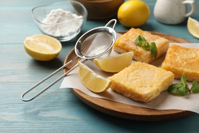 Tasty lemon bars and mint on light blue wooden table, closeup