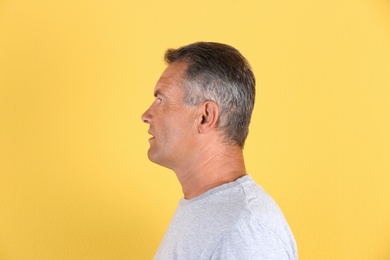 Mature man on color background. Hearing problem