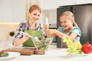 Photo of Mother and daughter cooking salad together in kitchen