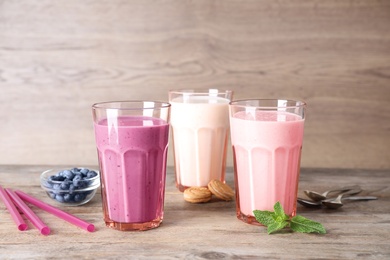 Photo of Different milk shakes in glasses on wooden table