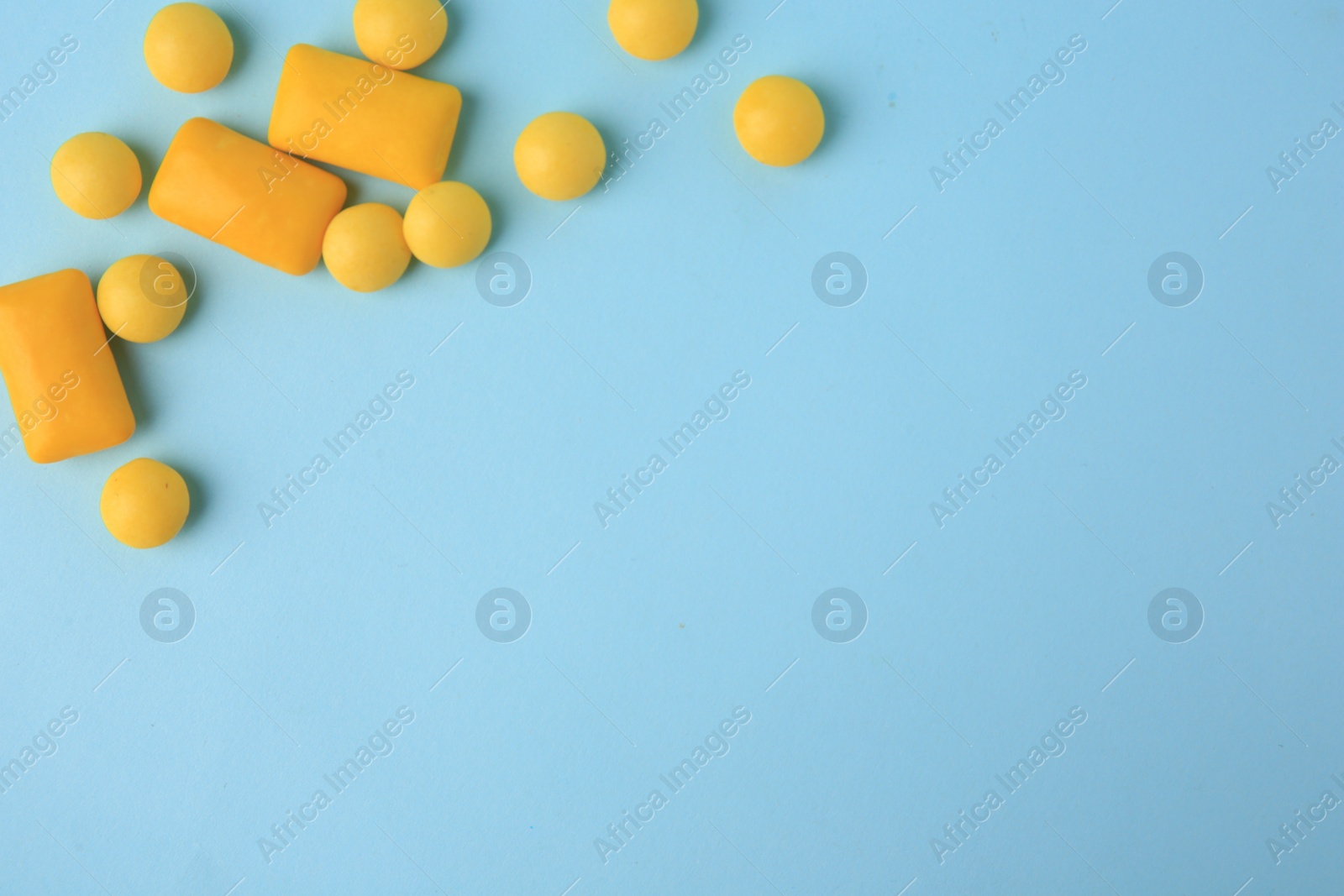 Photo of Many different chewing gums on light blue background, flat lay. Space for text