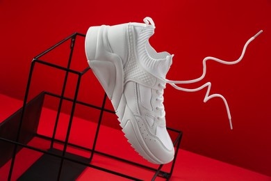 Photo of Stylish presentation of one sneaker on red background