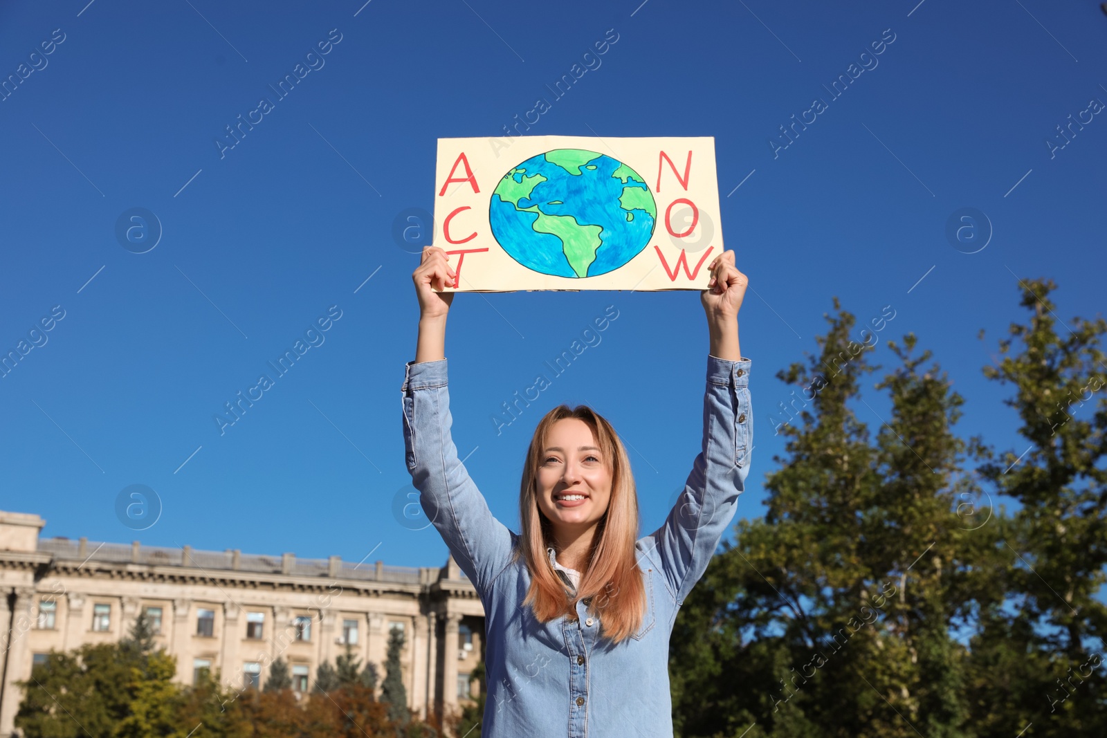 Photo of Young woman with poster protesting against climate change outdoors
