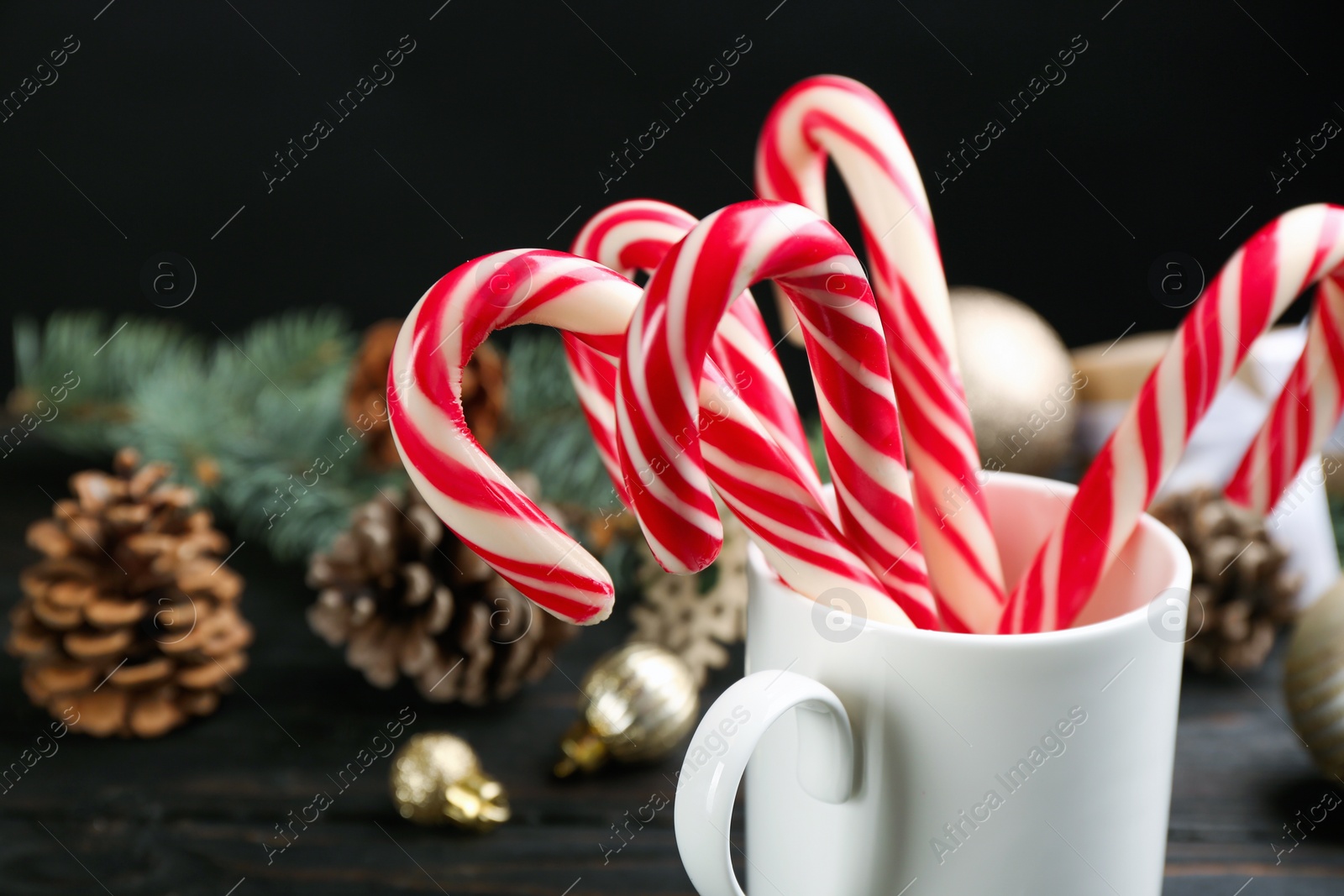 Photo of Many sweet candy canes and Christmas decor on black wooden table