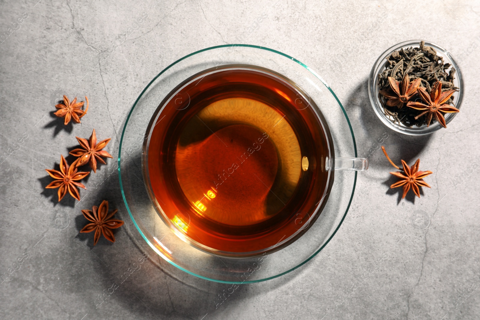 Photo of Aromatic tea with anise stars on light grey table, flat lay