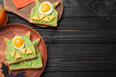 Photo of Halloween themed breakfast served on black wooden table, flat lay and space for text. Tasty sandwiches with fried eggs