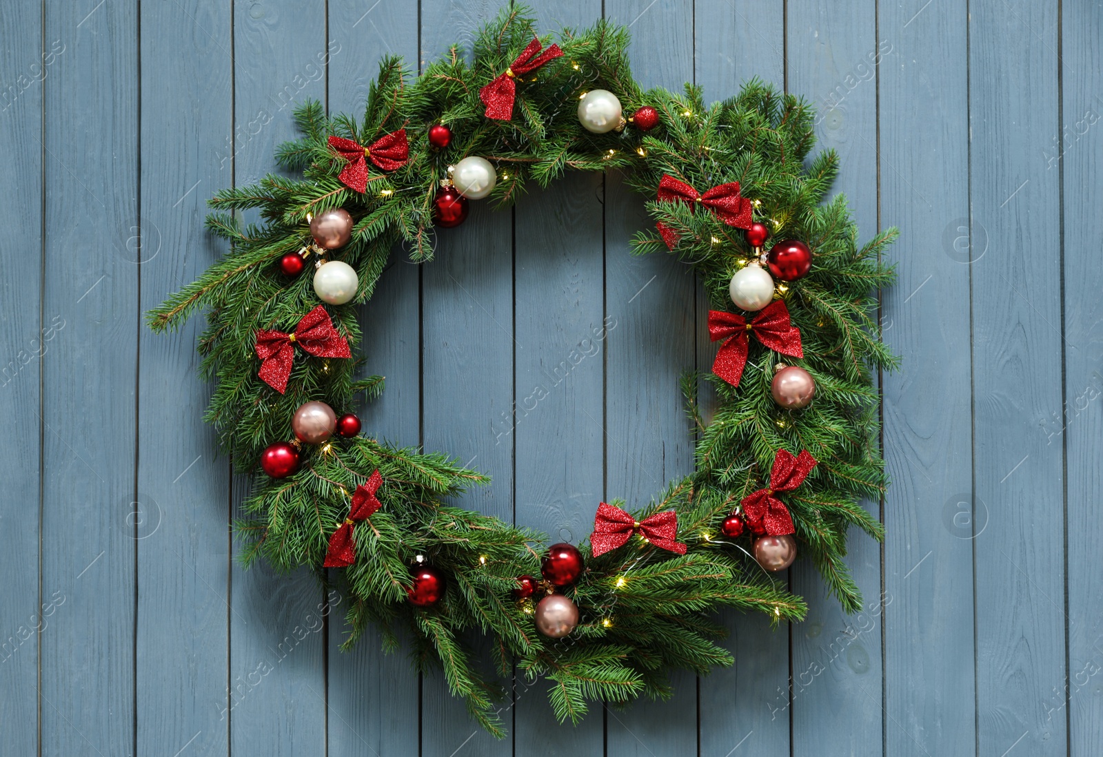 Photo of Beautiful Christmas wreath with festive decor on blue wooden background, top view