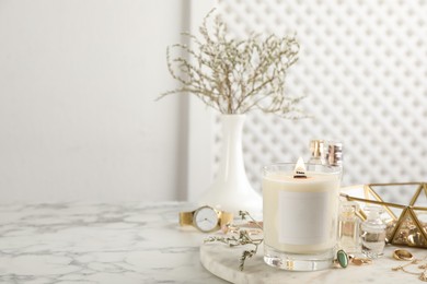 Composition with burning soy candle on white marble table, space for text