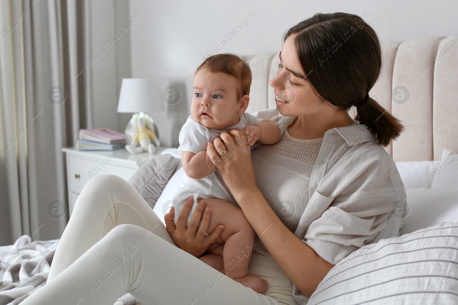 Photo of Young woman with her little baby on bed at home