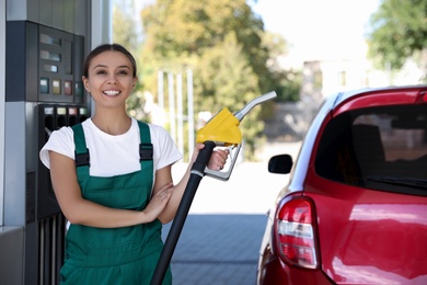 Photo of Young worker with fuel pump nozzle near car at modern gas station