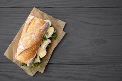 Tasty sandwich with brie cheese on grey wooden table, top view. Space for text