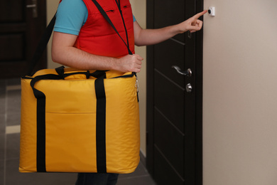 Male courier with thermo bag ringing doorbell, closeup. Food delivery service