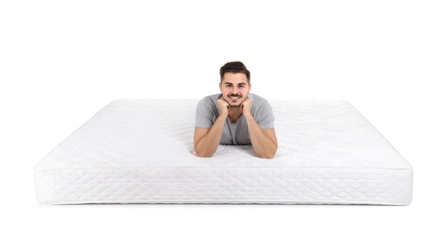 Young man lying on mattress against white background