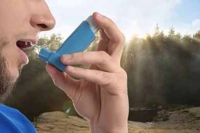 Man using asthma inhaler near forest, closeup. Emergency first aid during outdoor recreation
