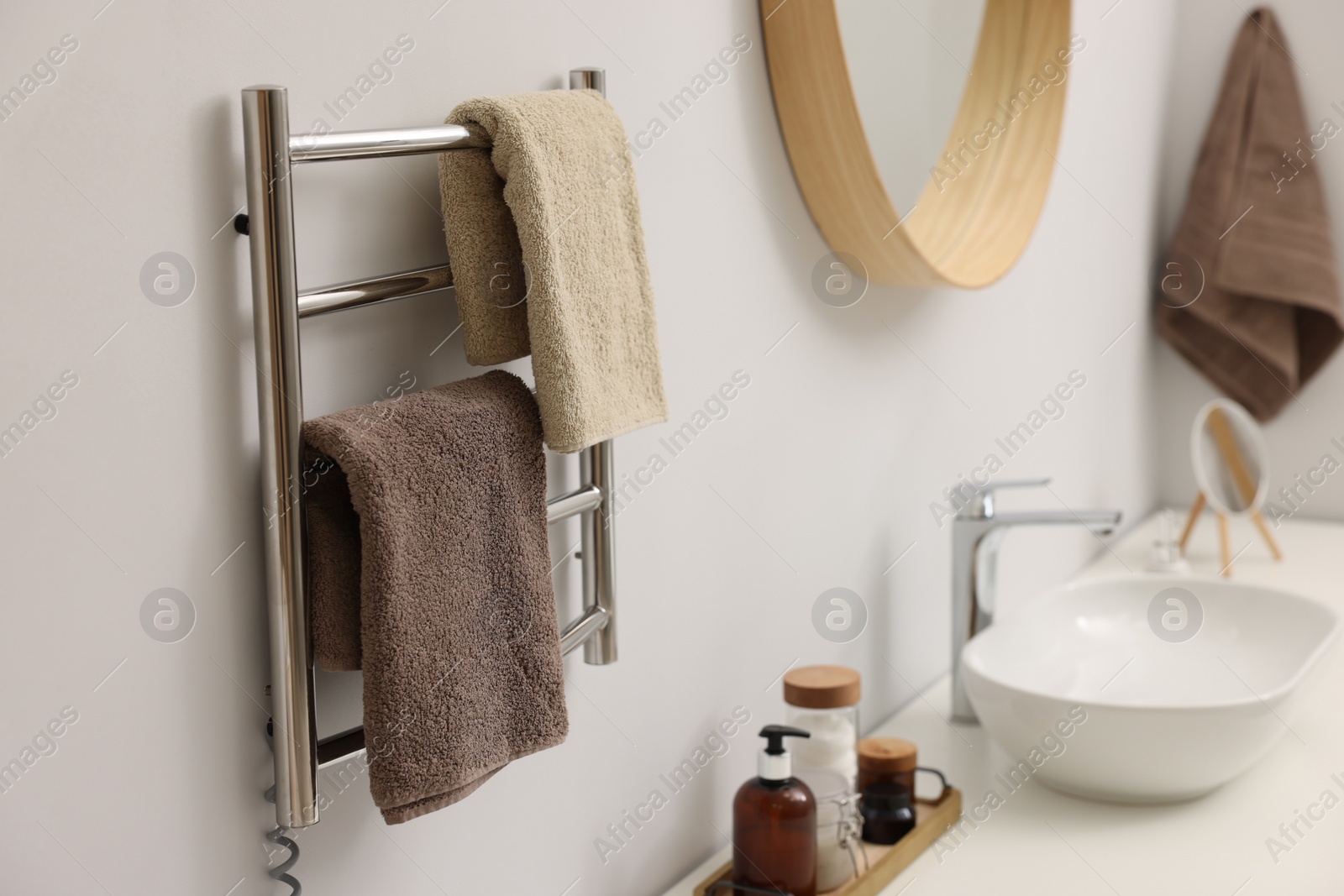 Photo of Heated towel rail with brown towels in bathroom