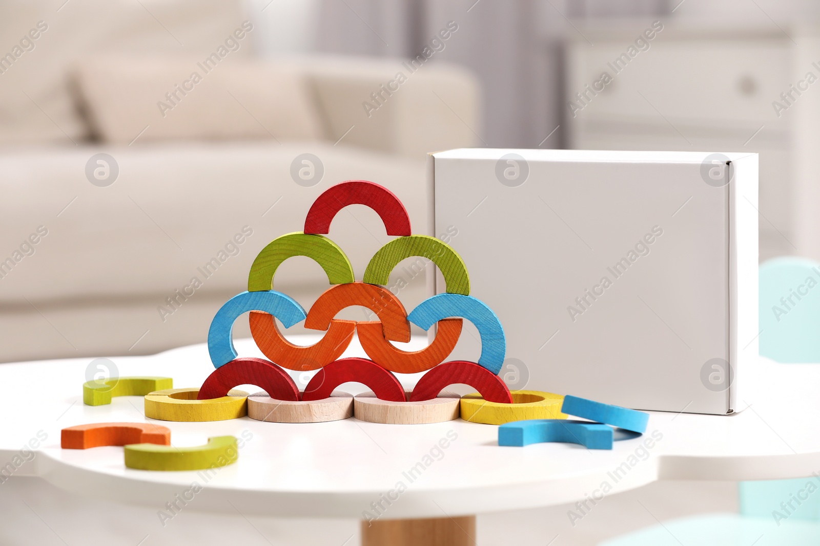 Photo of Colorful wooden pieces of playing set on white table indoors. Educational toy for motor skills development