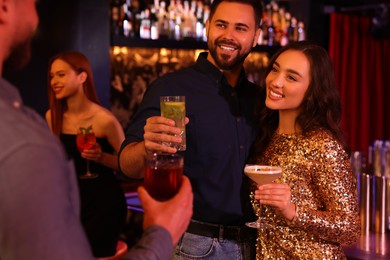 Photo of Happy friends with cocktails spending time together in bar