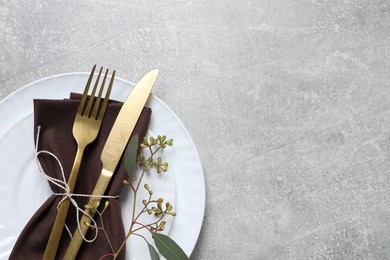 Stylish table setting with cutlery and eucalyptus leaves, top view. Space for text