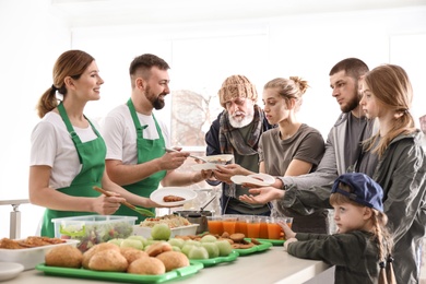 Photo of Volunteers giving food to poor people indoors