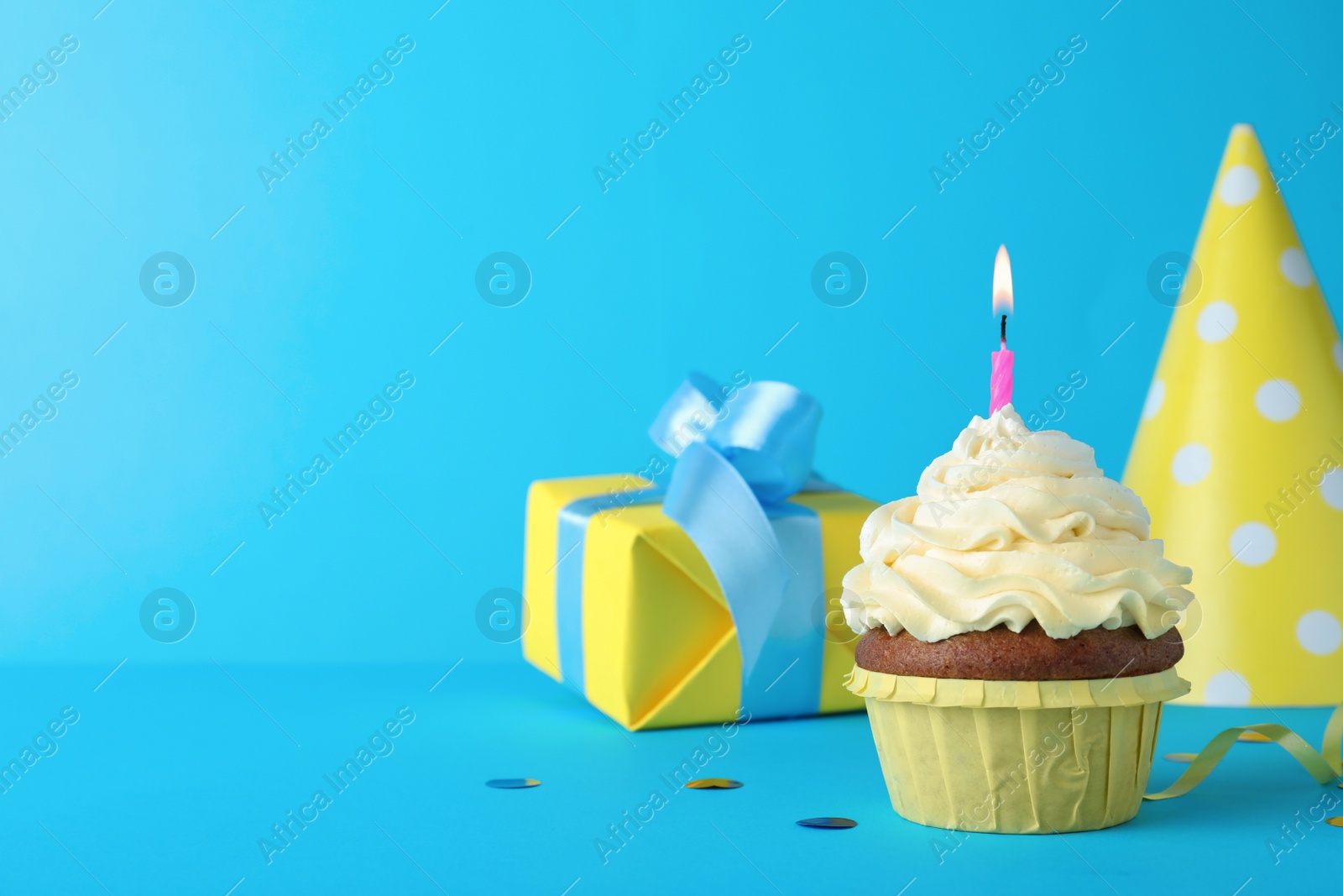 Photo of Delicious birthday cupcake with candle on light blue background, space for text