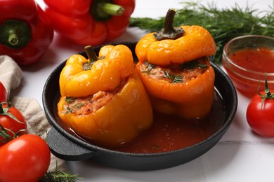 Photo of Tasty stuffed peppers and products on light tiled table, closeup