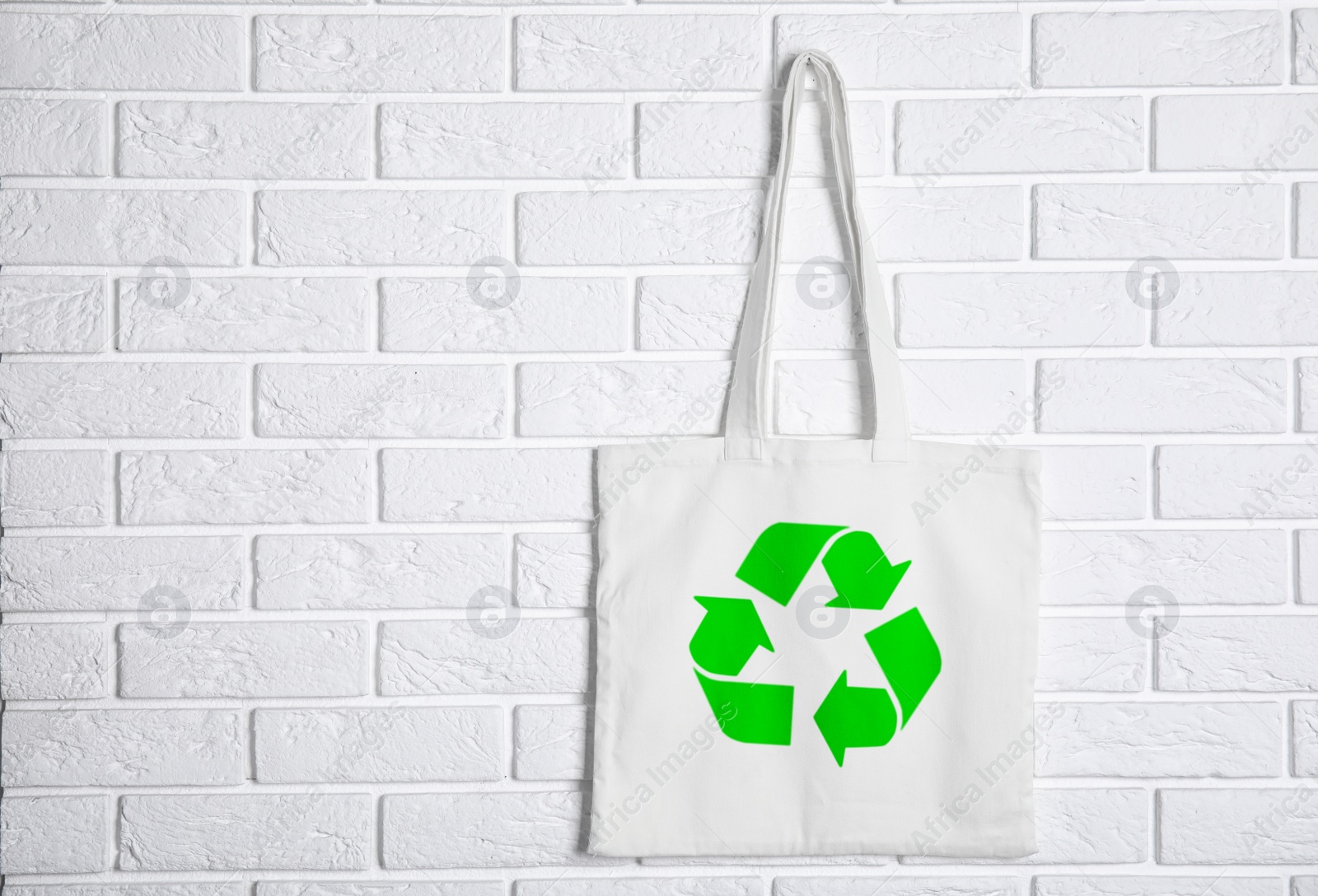 Image of Bag with recycling symbol hanging on brick wall. Space for text