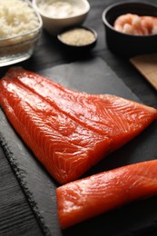 Photo of Fresh salmon for sushi on black wooden table, closeup