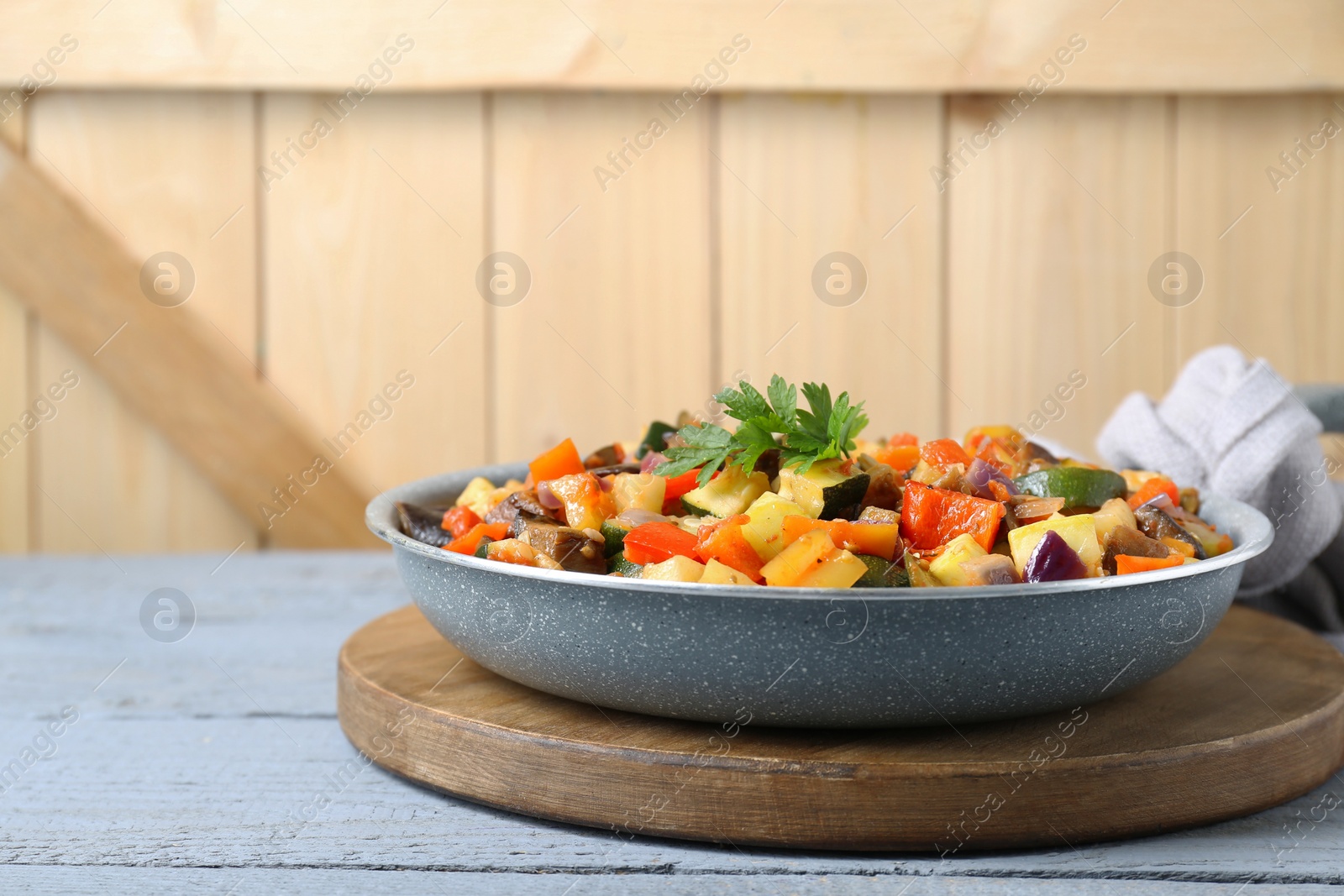 Photo of Delicious ratatouille in frying pan on grey wooden table, space for text