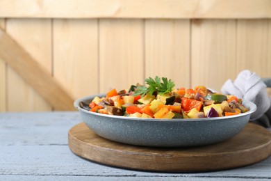 Delicious ratatouille in frying pan on grey wooden table, space for text
