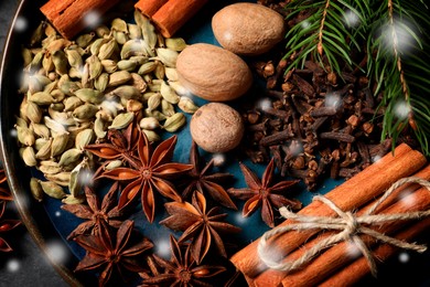 Different spices and fir tree branches on plate, top view. Cinnamon, cloves, anise, cardamom, nutmegs